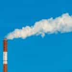 a smokestack with a cloud of smoke in the sky