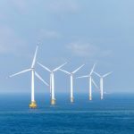 a row of wind turbines in the middle of the ocean