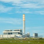 a factory with a large tower in the middle of a field