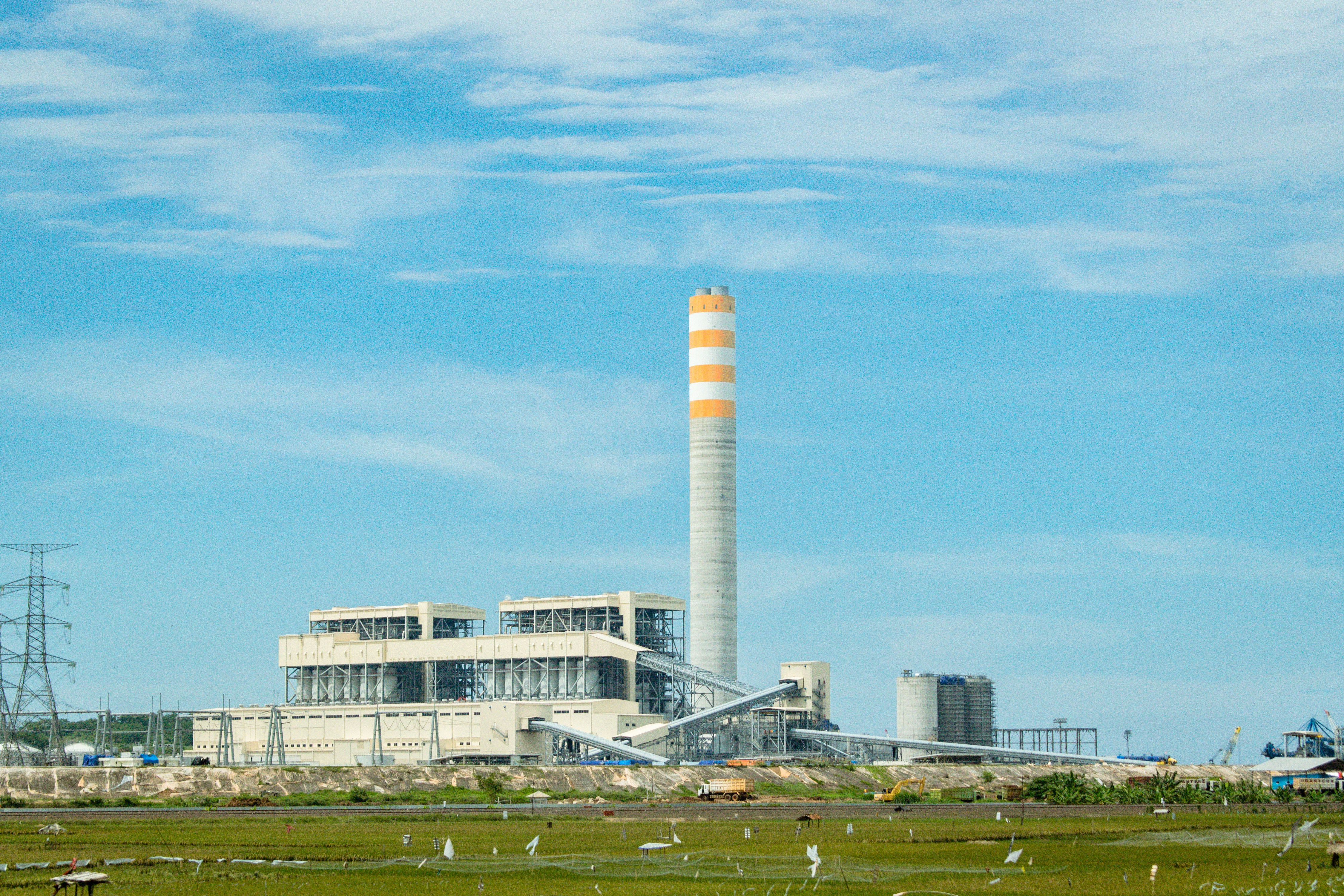 a factory with a large tower in the middle of a field