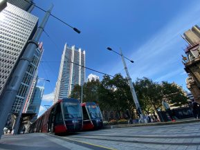 A train traveling down a street next to tall buildings