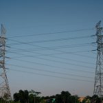 Power lines stand tall against a clear blue sky.