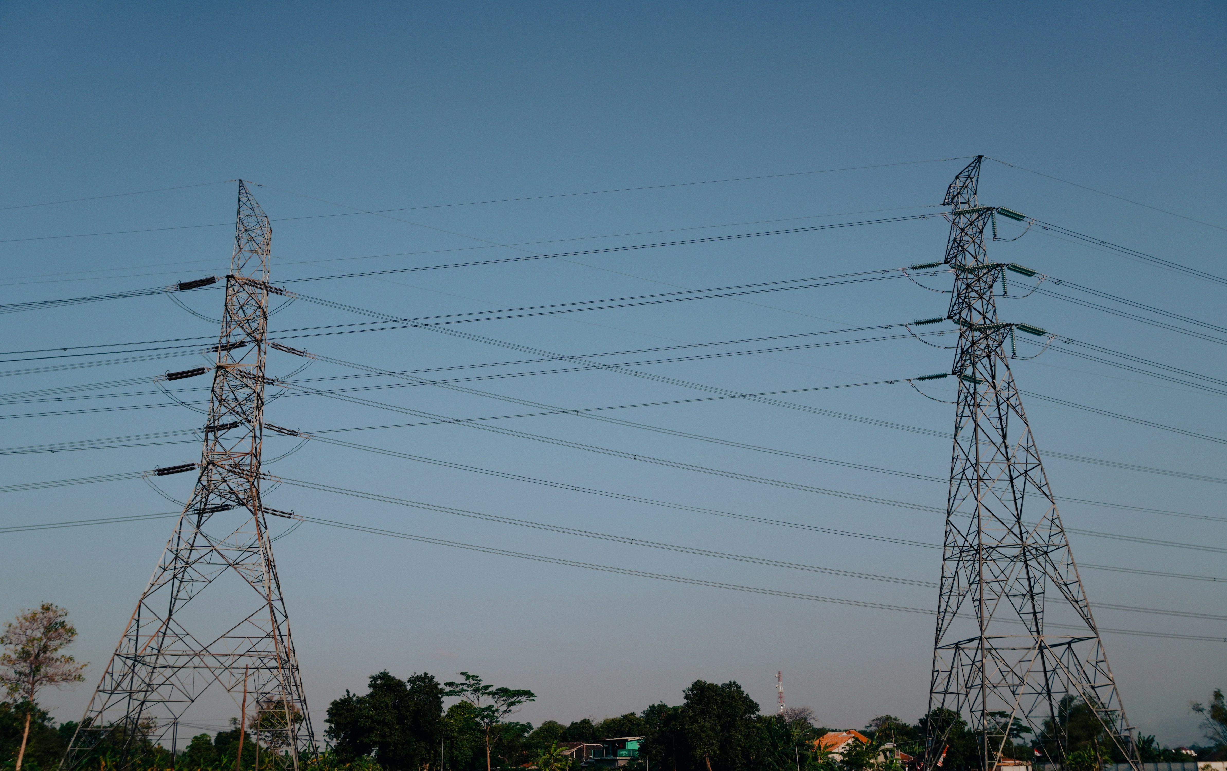Power lines stand tall against a clear blue sky.