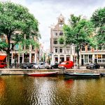 a group of boats floating on top of a river next to tall buildings