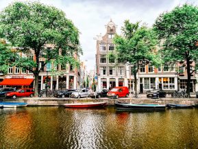 a group of boats floating on top of a river next to tall buildings