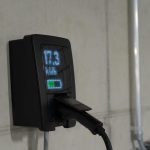 Electric car charger mounted on wall with display.