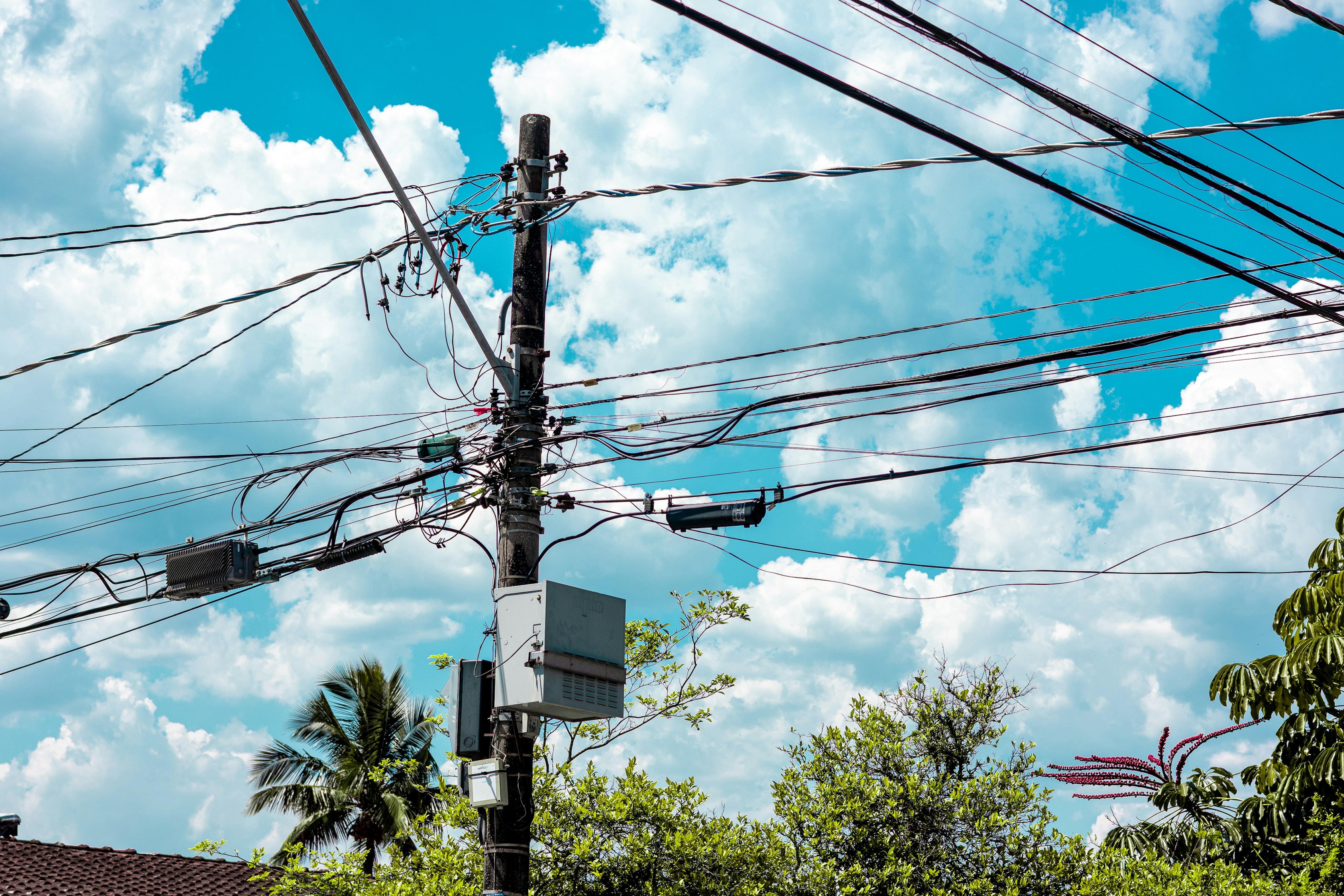 A utility pole with many wires against a blue sky.