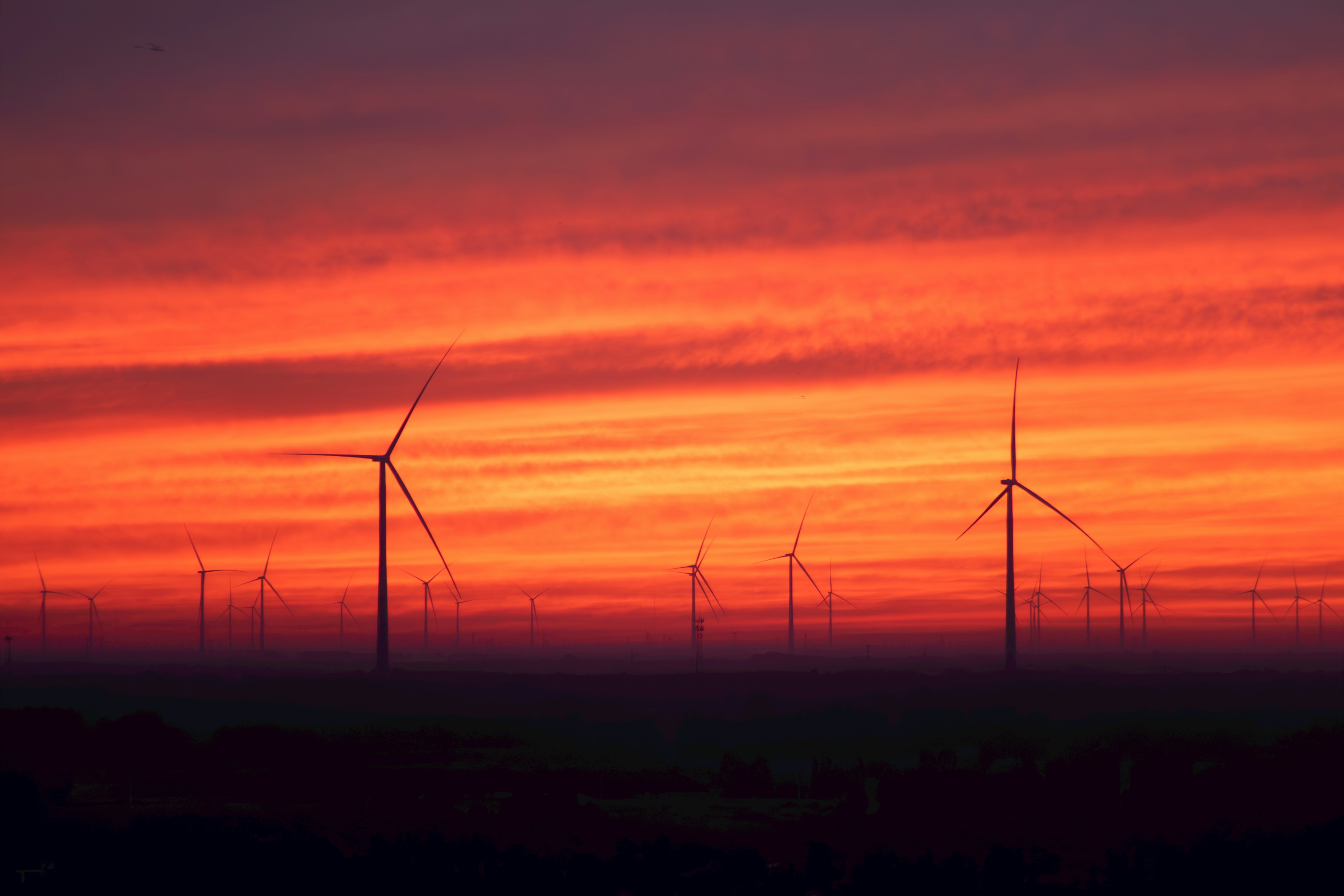 Wind turbines silhouetted against a vibrant sunset sky