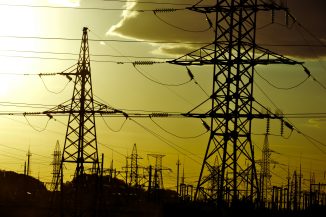 Power lines stand against a yellow sky.