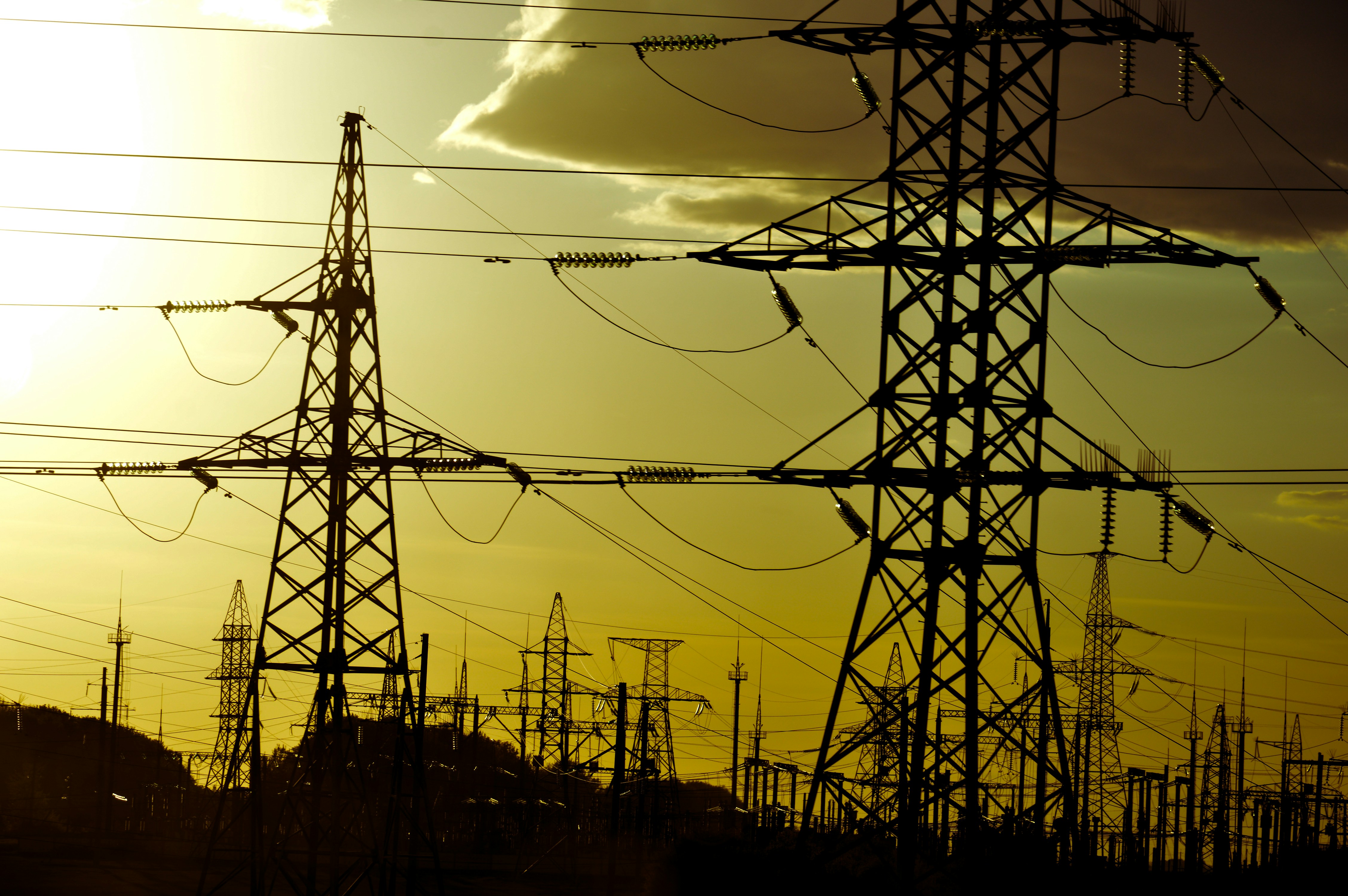 Power lines stand against a yellow sky.