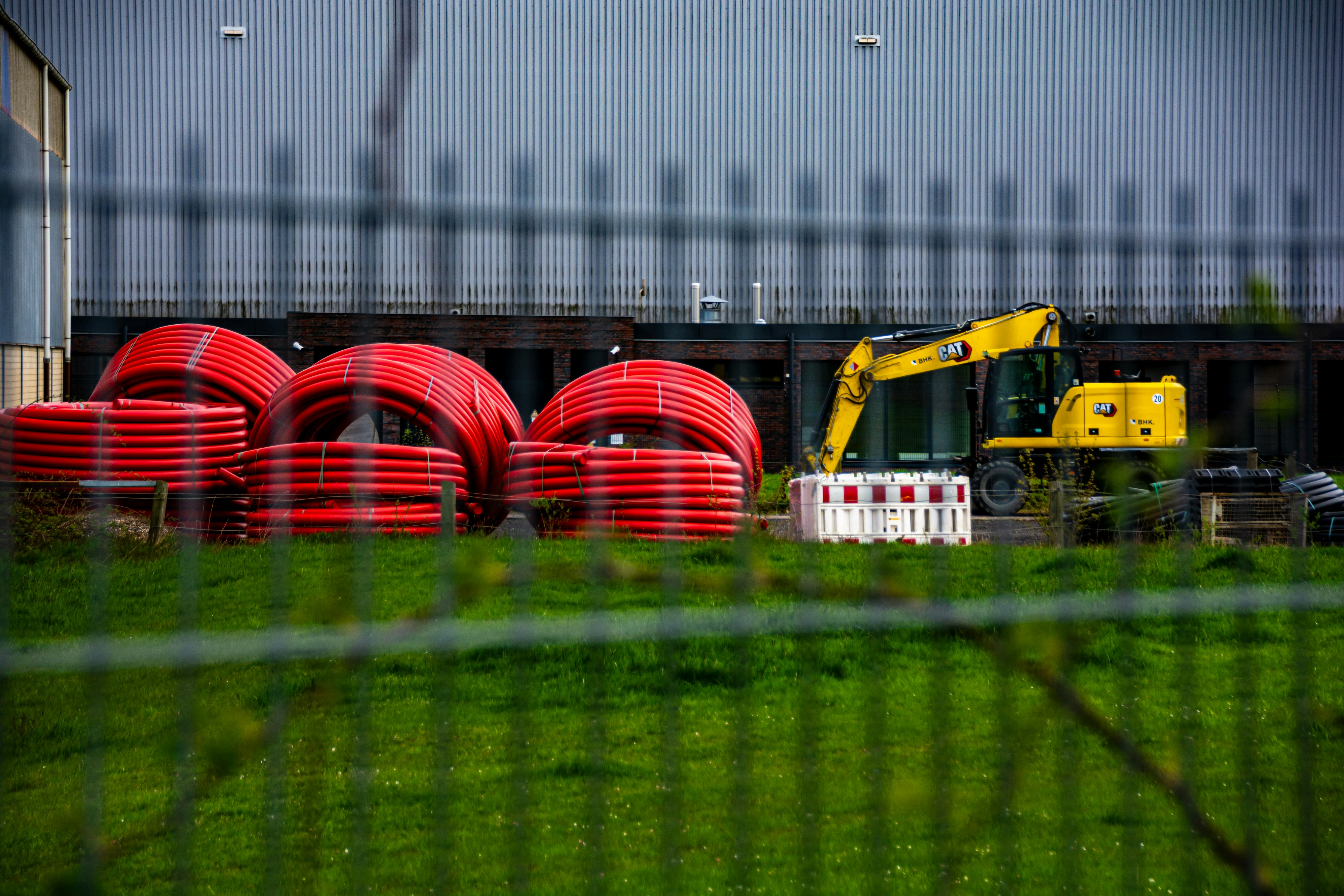 Yellow excavator near stacked red coils