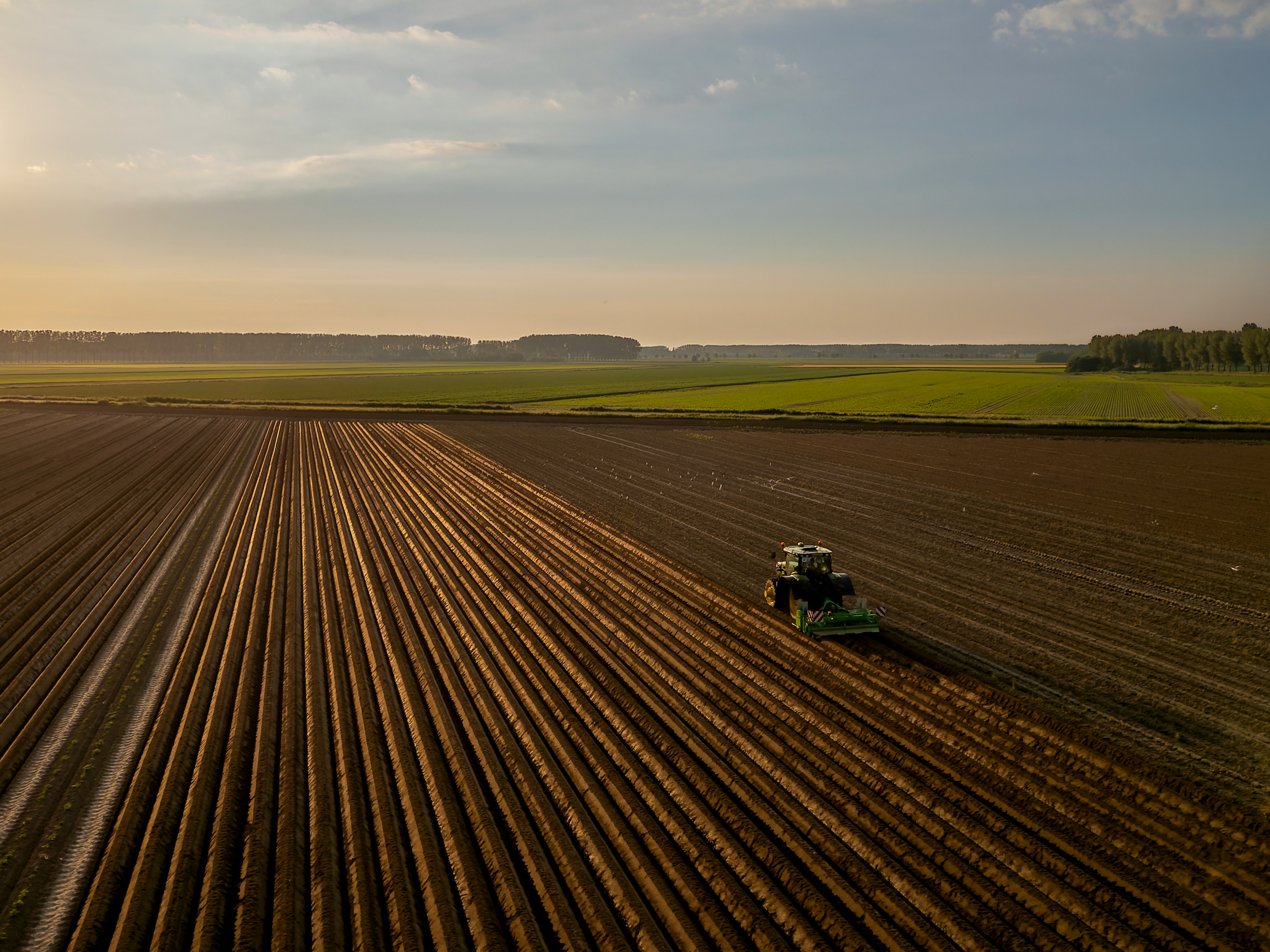 a tractor plowing a field at sunset